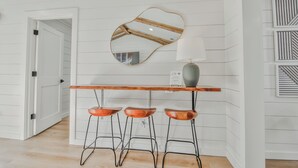 A kitchen with a wooden bar, three stools, a mirror, and a lamp. - The Pops-Stylish newly remodeled 3-bedroom house with indoor/outdoor living area (Lubbock)