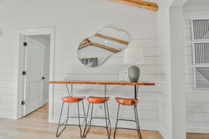 Eine Küche mit einer Holztresore, drei Barhocker, einem Spiegel und einer Lampe.