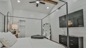 A bedroom with a bed, a dresser, a mirror, and a ceiling fan. - The Pops-Stylish newly remodeled 3-bedroom house with indoor/outdoor living area (Lubbock)