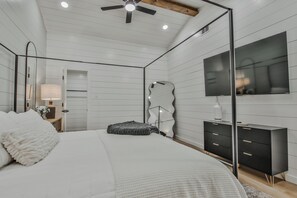 Ein Schlafzimmer mit Bett, Schminktisch, Spiegel und Deckenventilator.