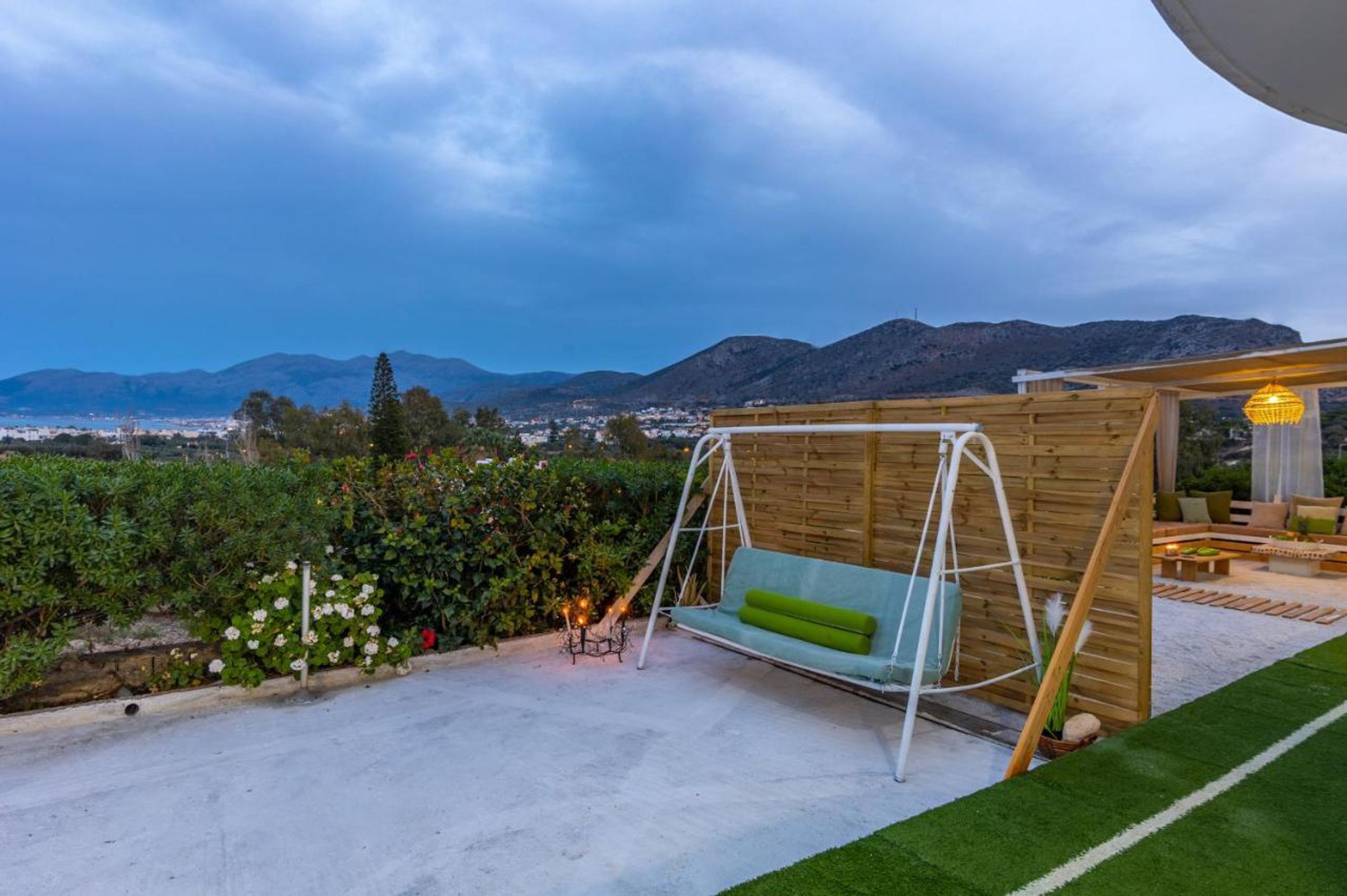 A patio with a swing, a wooden pergola, and a view of distant mountains.