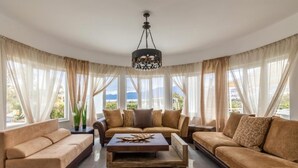 A spacious living room with a large sofa set, a coffee table, and a chandelier. - White Cycladic House With Jacuzzi (Hersonissos)