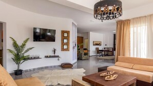 A modern living room with a sofa, coffee table, and a TV mounted on the wall. - White Cycladic House With Jacuzzi (Hersonissos)