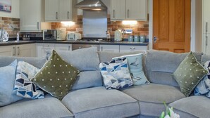 A modern kitchen with white cabinets, a stainless steel range hood, and a wooden door. - 1 bedroom accommodation in Carnforth (Carnforth)