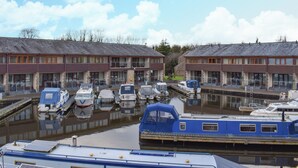 A marina with several boats docked in calm water, surrounded by buildings with a modern architectural style. - 1 bedroom accommodation in Carnforth (Carnforth)