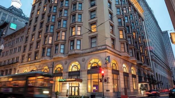 Un edificio grande y antiguo de varios pisos, con ventanas en arco y una entrada destacada.