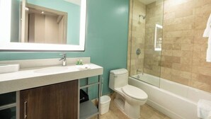 Un baño moderno con un espejo grande, un lavabo, un inodoro y una ducha con cerramiento de vidrio.