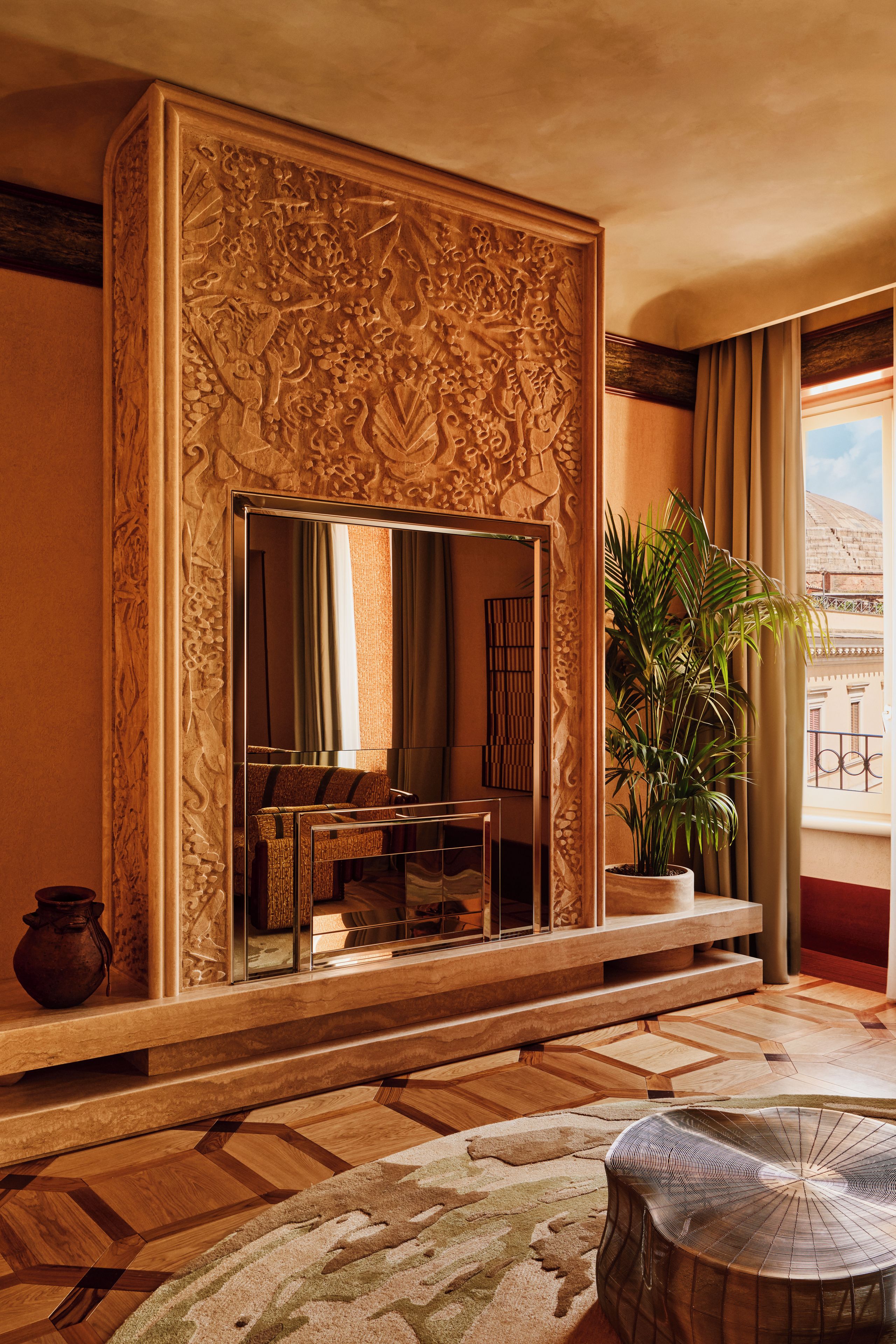 A room with a large mirror, a sofa, a potted plant, and a patterned rug.
