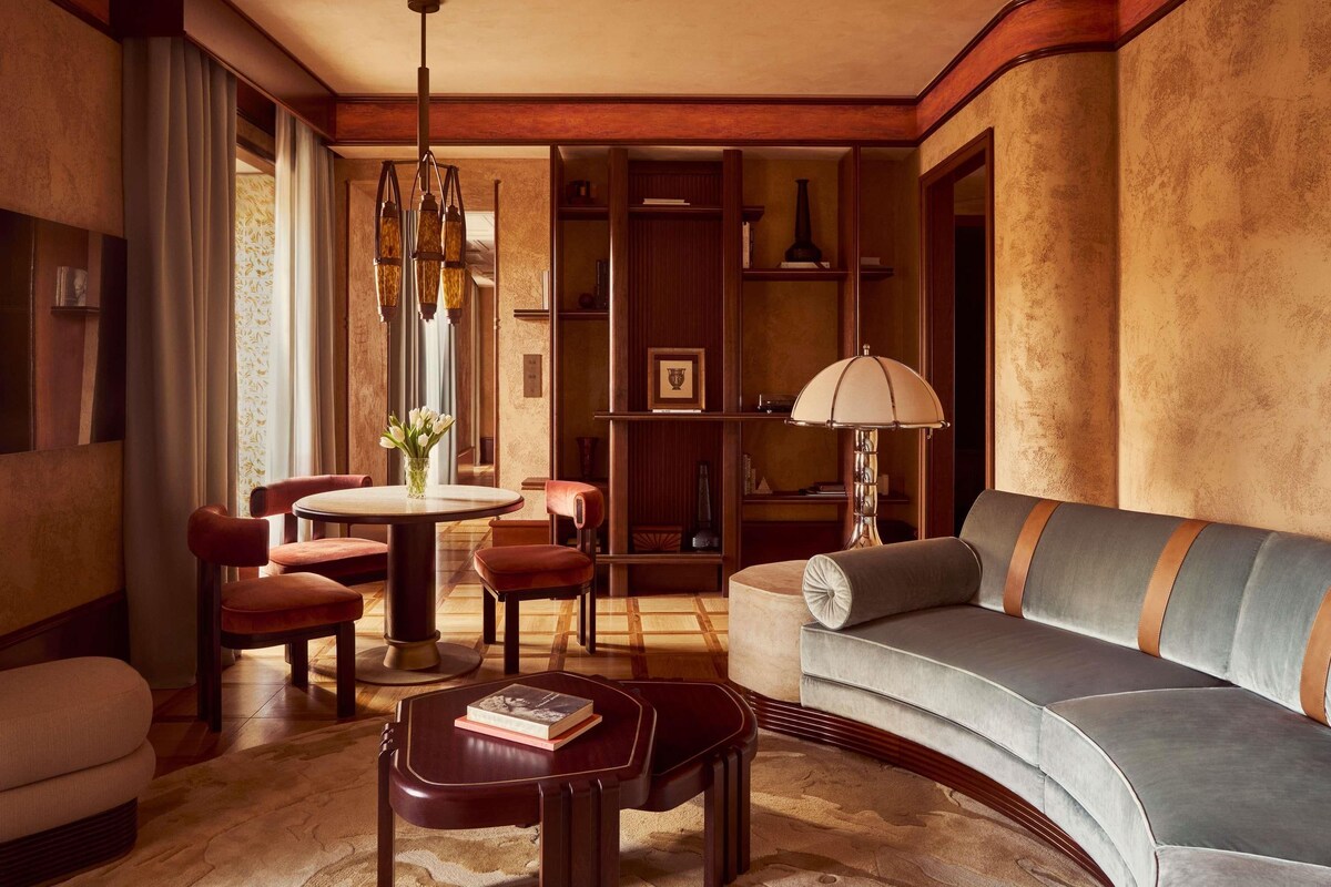 A well-lit living room with a sofa, chairs, a coffee table, and a bookshelf.