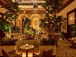 A luxurious lobby with a central seating area, multiple tables, and lush greenery. - Orient Express La Minerva (Rome)
