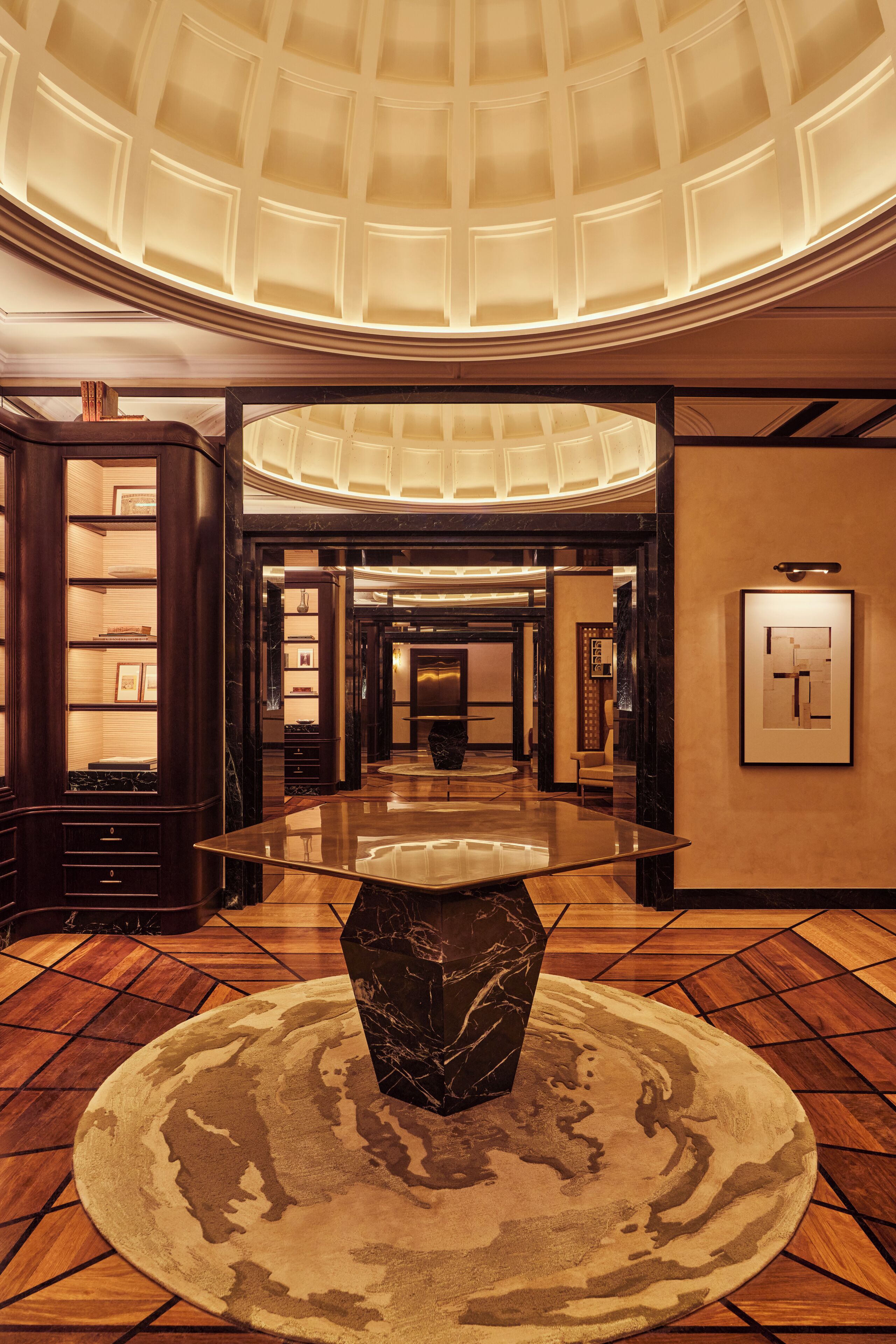 Un hall d’entrée spacieux, doté d’une table en verre au centre, d’un tapis à motifs et d’un plafond haut avec une verrière.