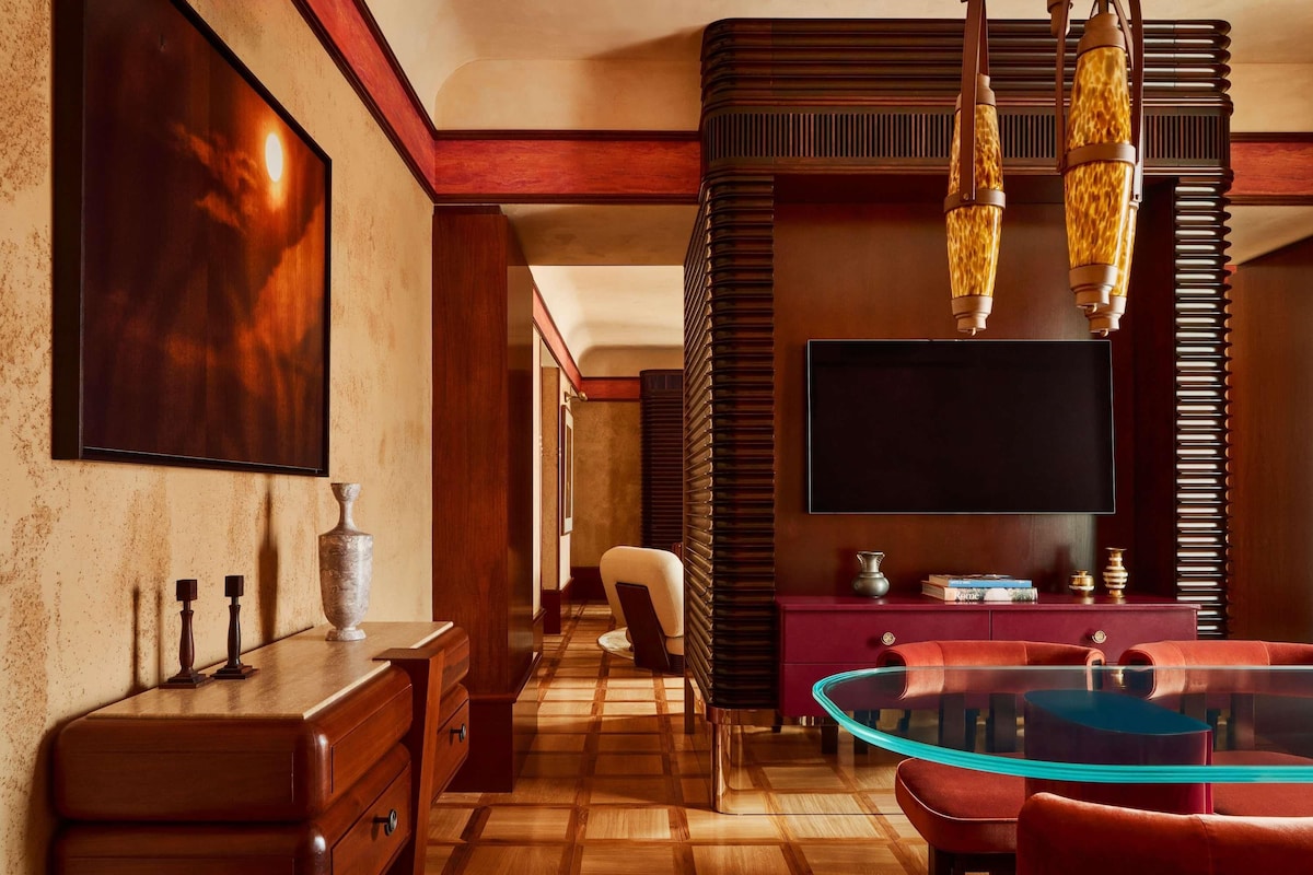 A modern interior with a wooden floor, a glass table, a red sofa, a TV, and a fireplace.
