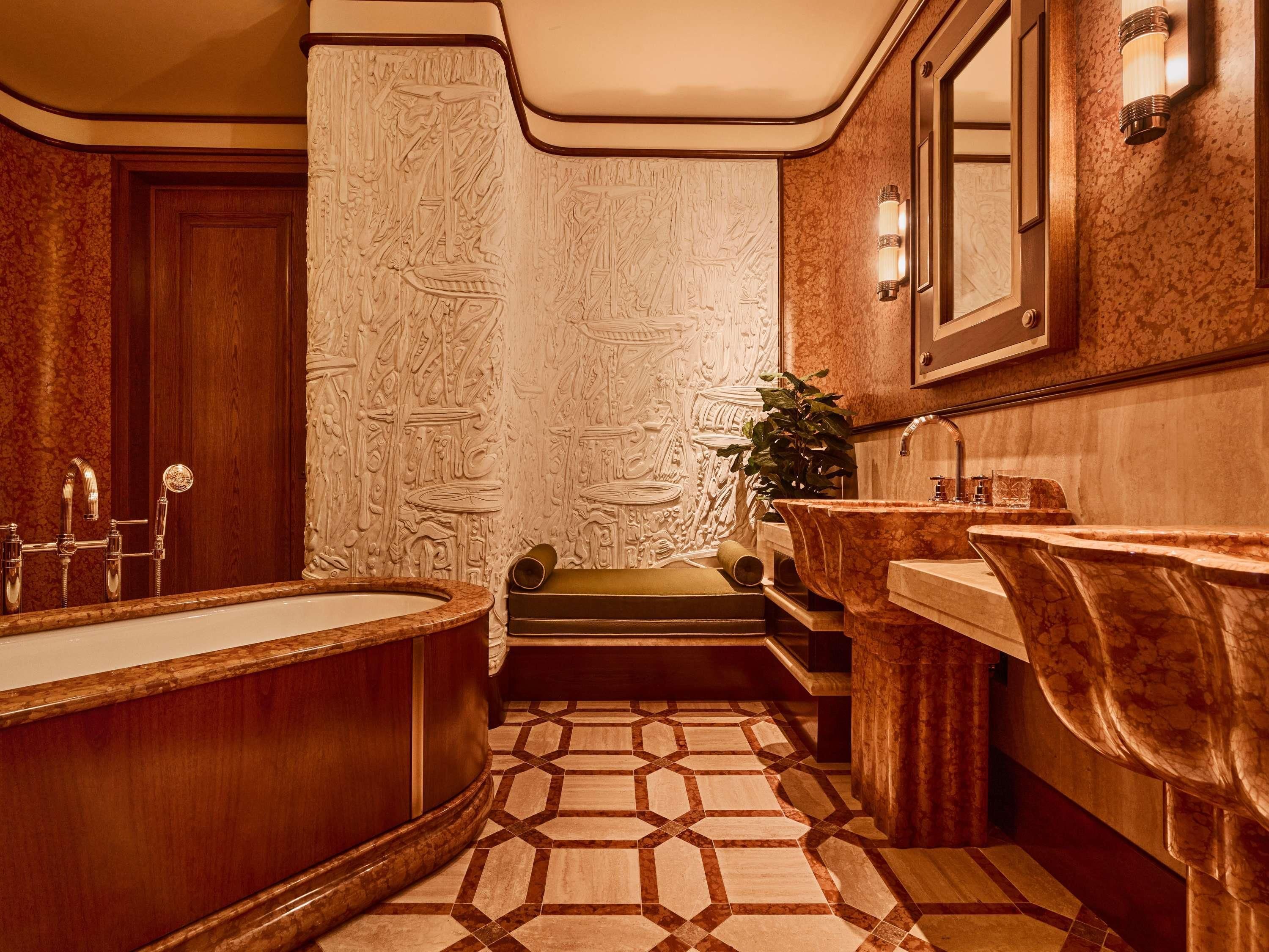 Un baño con una bañera independiente, un lavabo, un espejo y un suelo estampado.