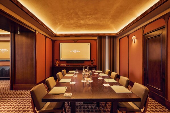 A conference room with a long table, chairs, a projector screen, and a carpeted floor. - Orient Express La Minerva (Rome)