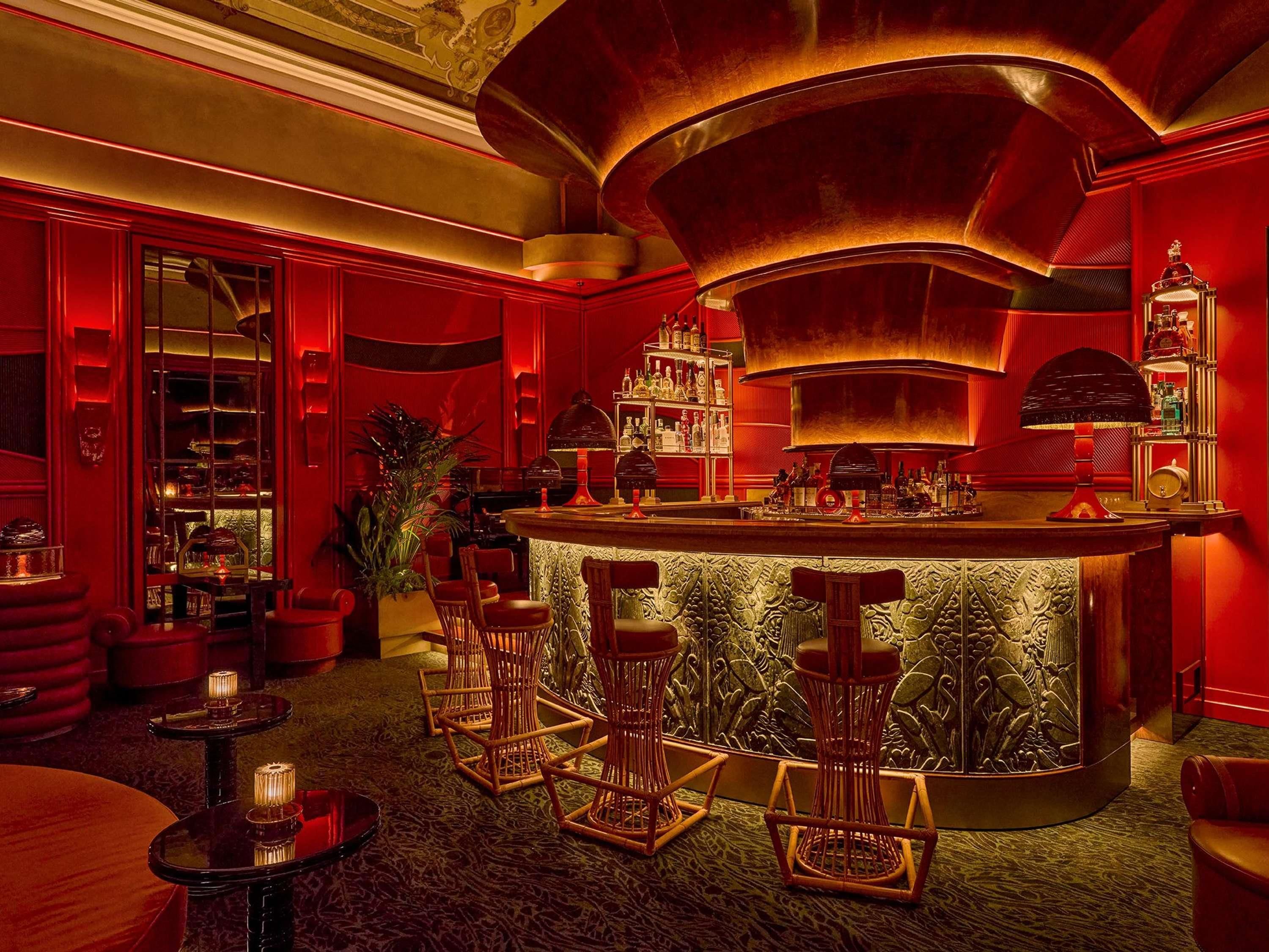 A bar area with a curved counter, bar stools, and a variety of bottles and glasses.