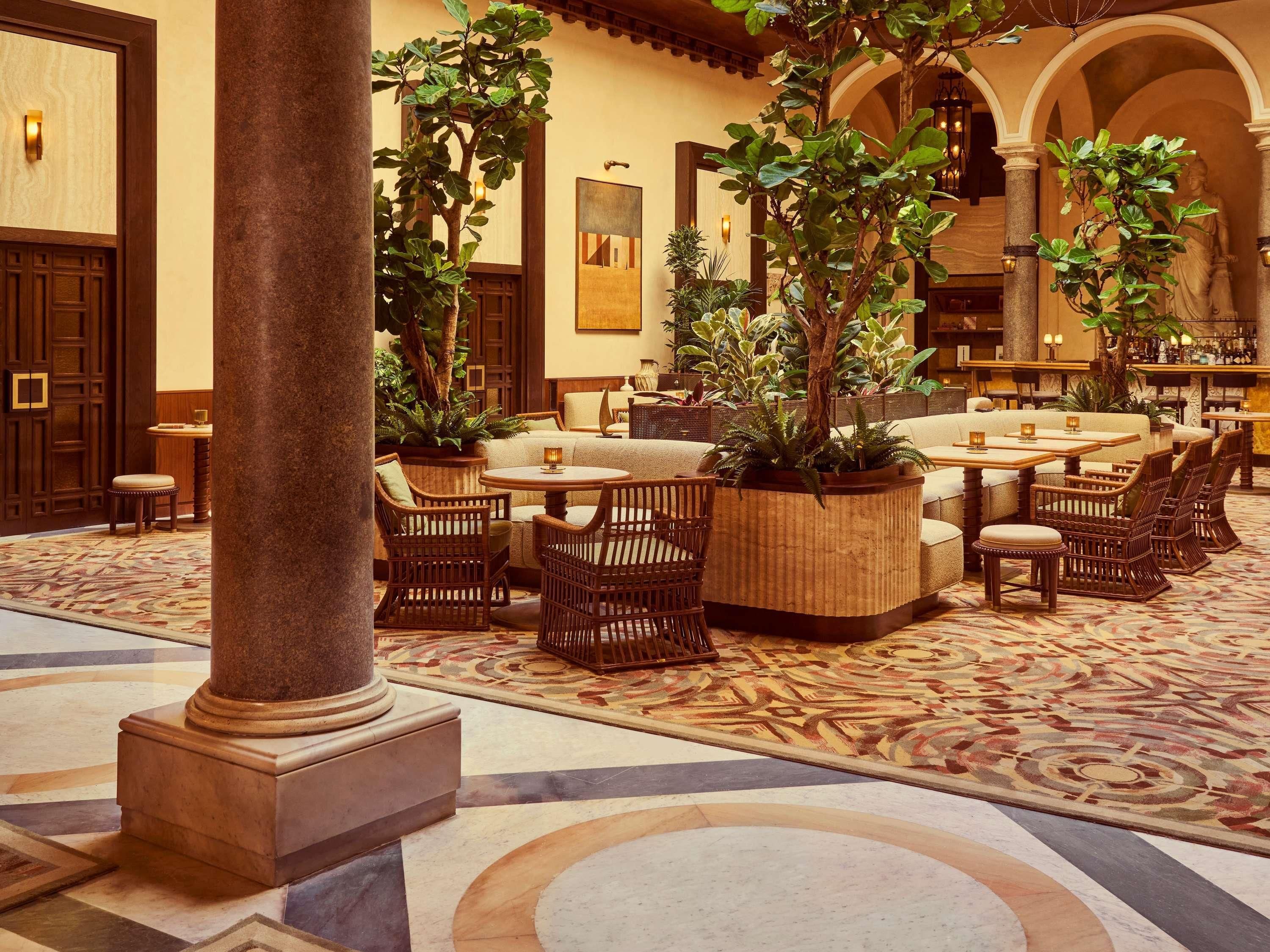A spacious indoor area with seating arrangements, columns, and potted plants.