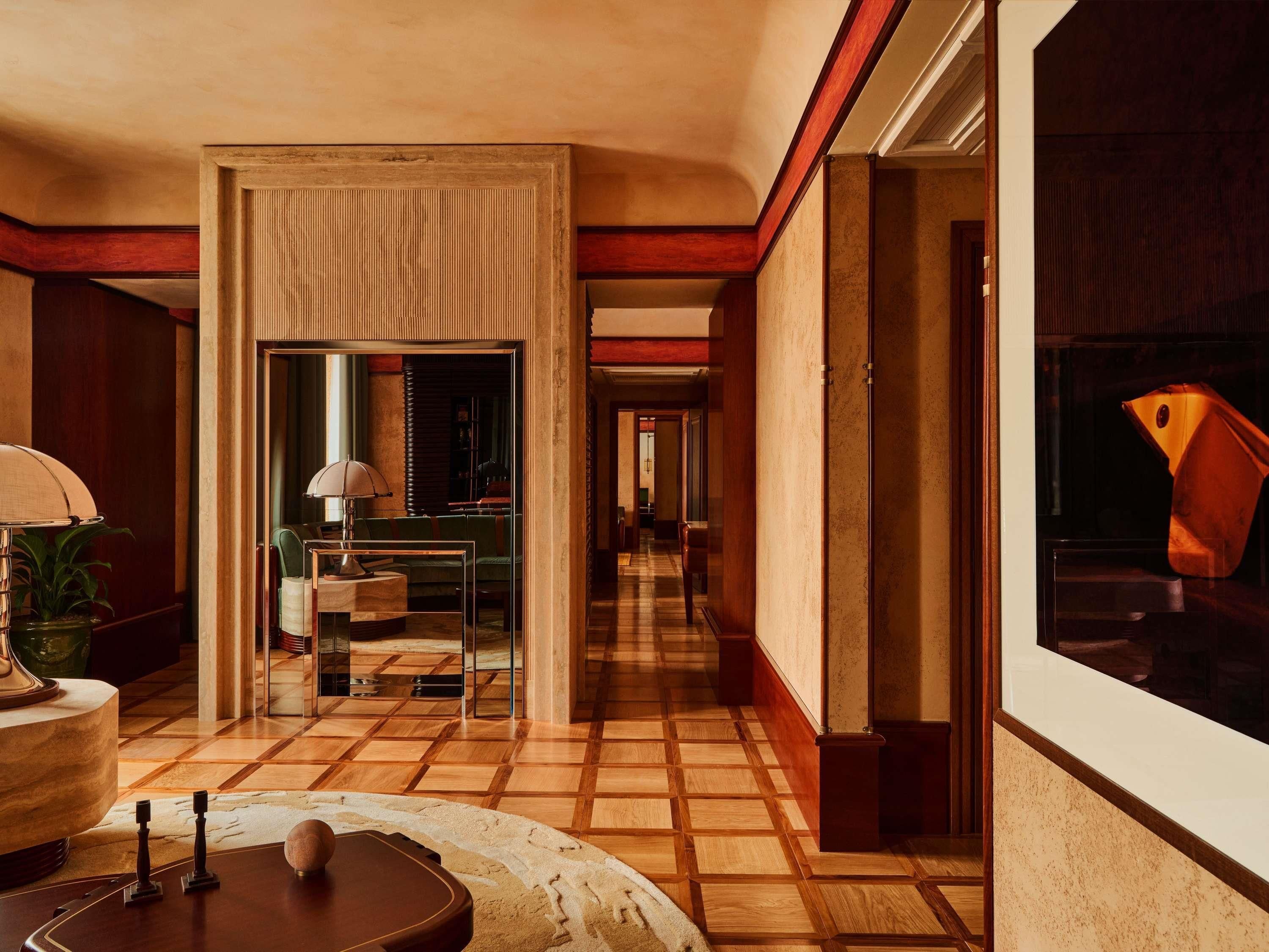A hotel lobby with a checkered floor, a lamp, a sofa, and a mirror.