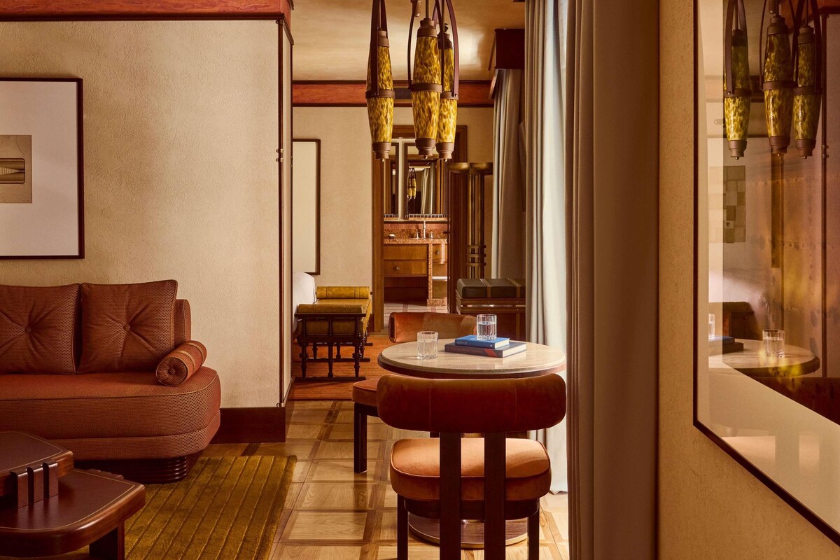 A cozy room with a leather sofa, a wooden coffee table, and a dining area with a chair and table.