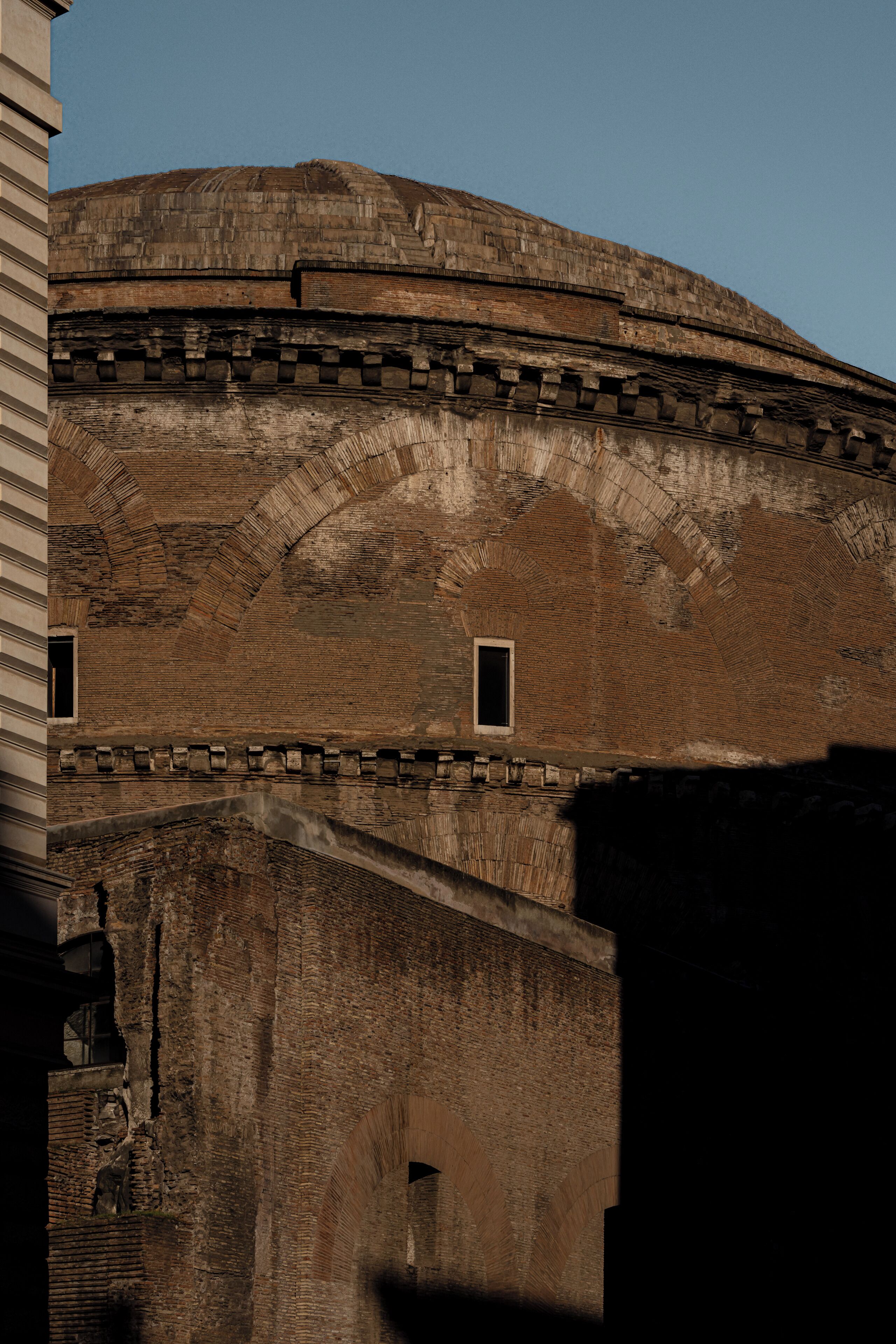 A historic building with arched brickwork and a dome.