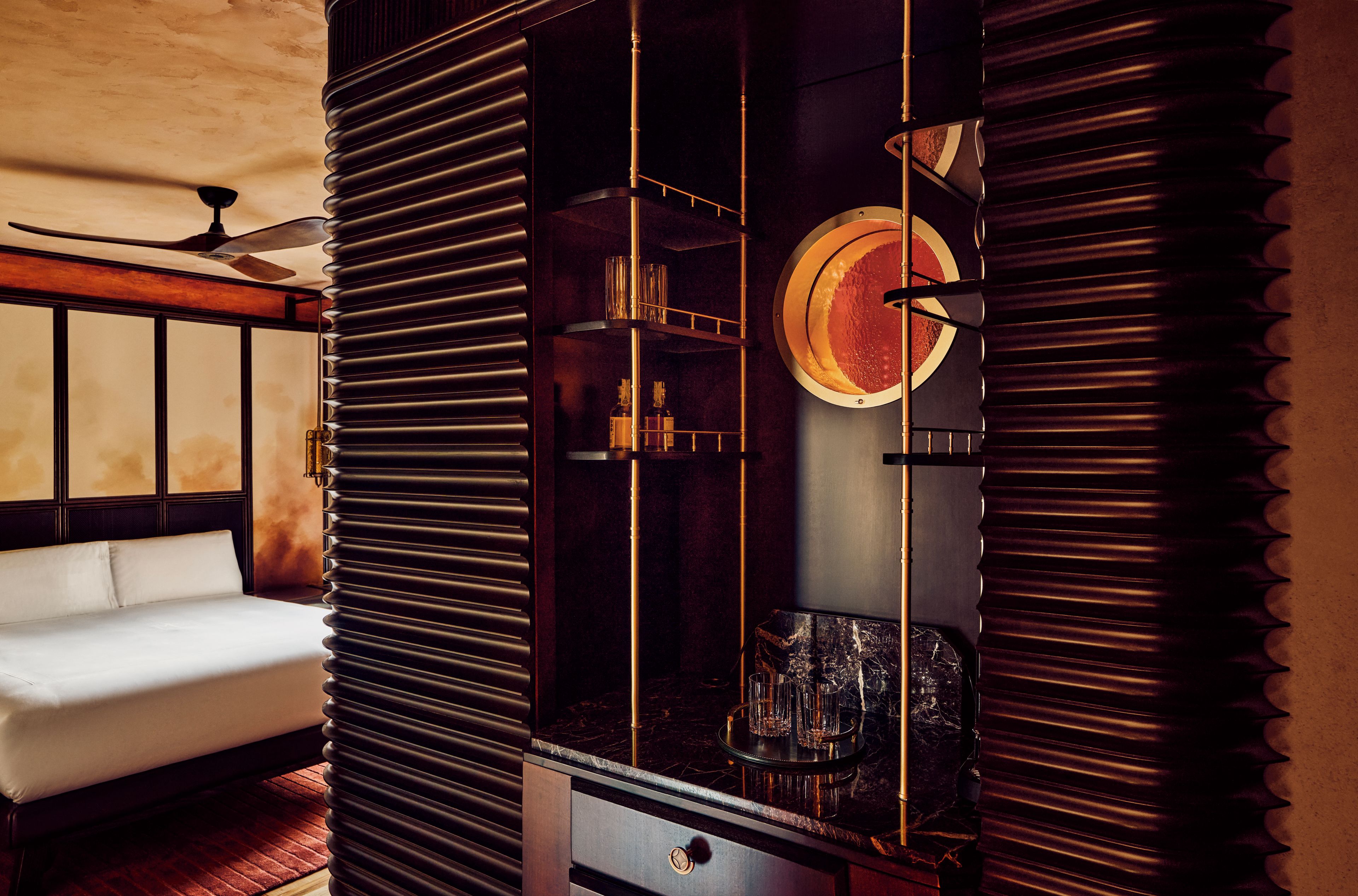 A modern interior with a sofa, a decorative wall with vertical slats, and a circular wall-mounted object.