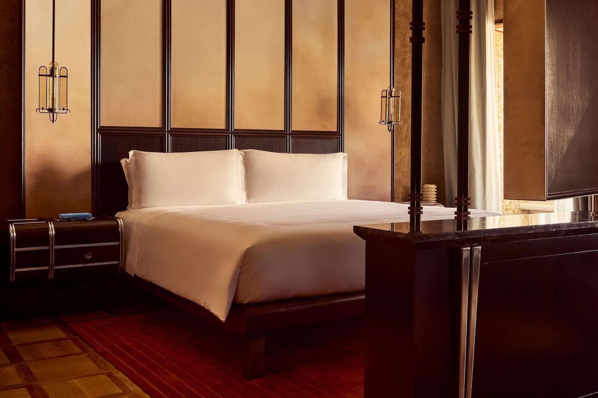 Une chambre d’hôtel avec un lit, des tables de chevet, un bureau et une grande fenêtre.