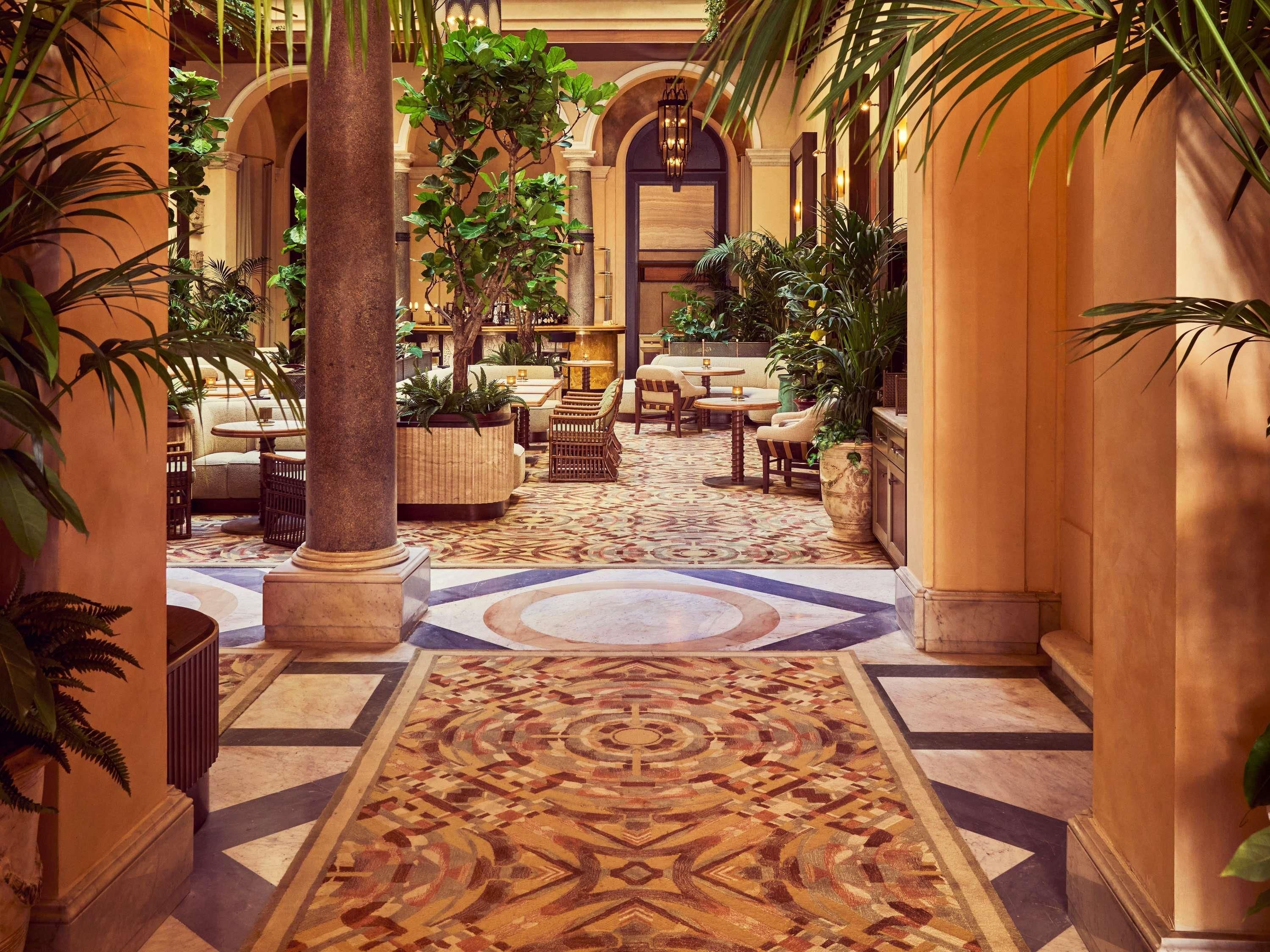 A hotel lobby with a patterned carpet, seating areas, and columns.