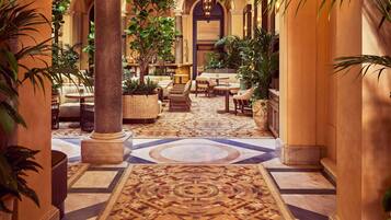 A hotel lobby with a patterned carpet, seating areas, and columns.