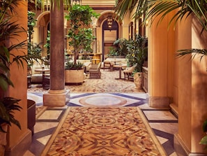 Un hall d’hôtel avec un tapis à motifs, des espaces aménagés pour s’asseoir et des colonnes.
