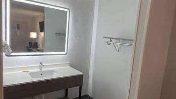 Un baño con un espejo grande, un lavabo, un perchero para toallas y una zona de ducha.