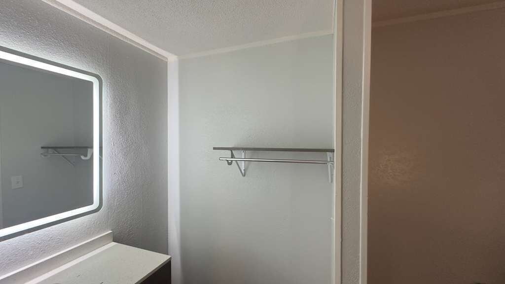 A bathroom with a mirror, a towel rack, and a door.