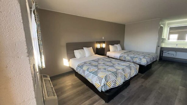 Une chambre d’hôtel avec deux lits, un radiateur et une fenêtre avec des rideaux.