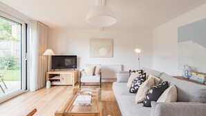 Een moderne woonkamer met een bank, salontafel, televisie en kunstwerk.
