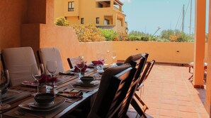 A dining area with a table set for four, chairs, and a view of a building in the background. - - BayAltea (Altea)