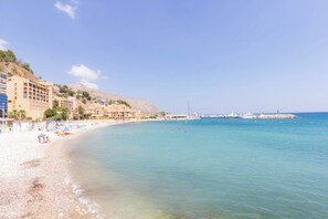 A beach with clear blue water, a sandy shore, and buildings along the coastline. - - BayAltea (Altea)
