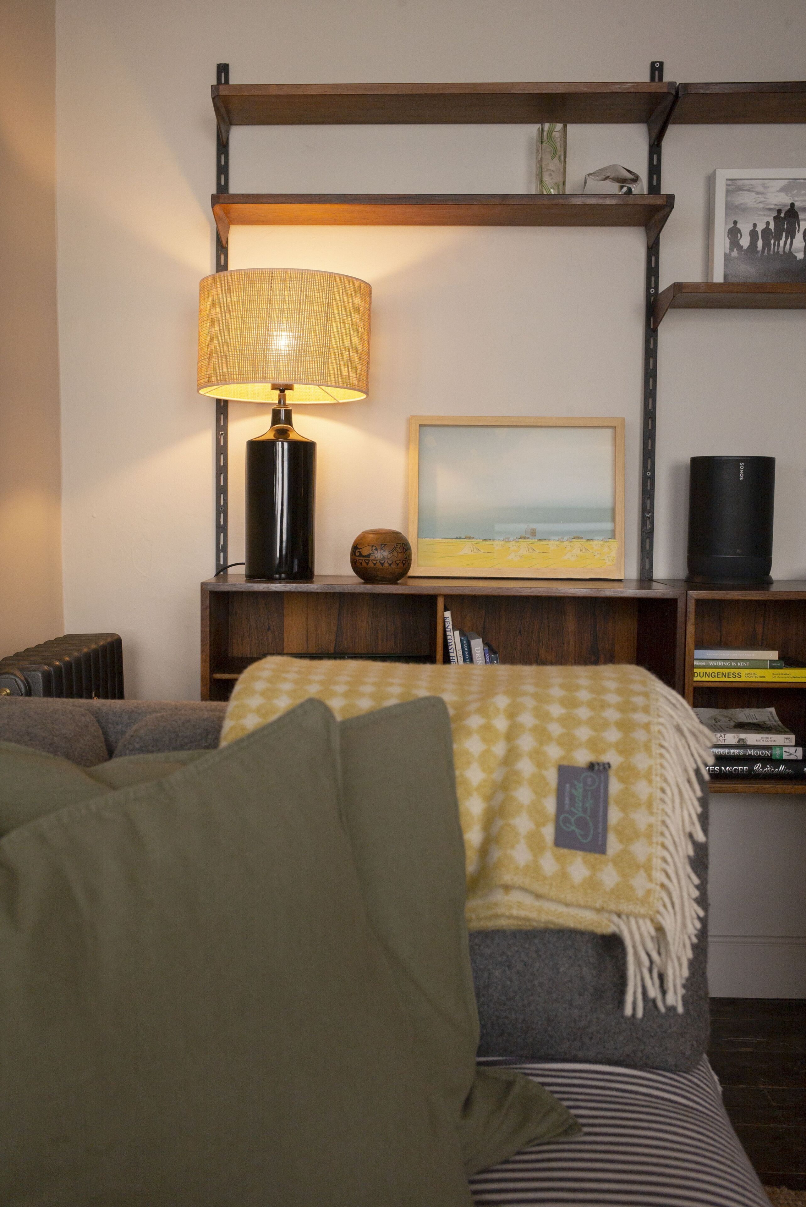 A cozy room with a bed, a lamp, a shelf with books, and a framed picture.