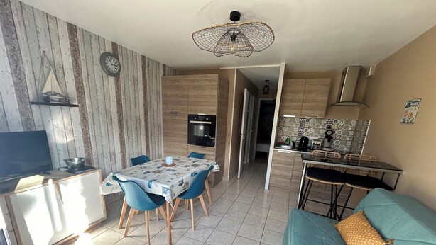 A compact living space with a dining area, kitchenette, and a sofa.