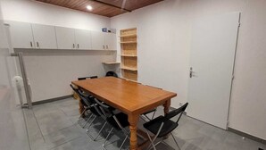 Une cuisine de taille réduite avec des meubles blancs, une table en bois et une étagère intégrée.