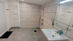 Une salle de bain avec un lavabo blanc, un miroir et des murs carrelés.