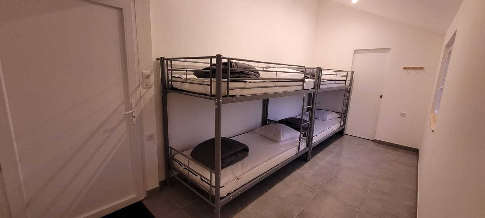 A room with bunk beds, a door, and a tiled floor.