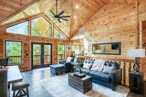 A spacious living room with a large sofa, a coffee table, and a dining area with a table and chairs. - Gatlinburg*Sleeps 8*Game Room (GATLINBURG)