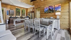 Ein Holzblockhaus-Innenraum mit Küche, Essbereich und großen Fenstern.