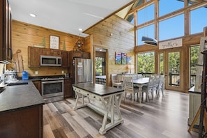 A spacious kitchen with wooden walls, a dining area, and a view of the outdoors.