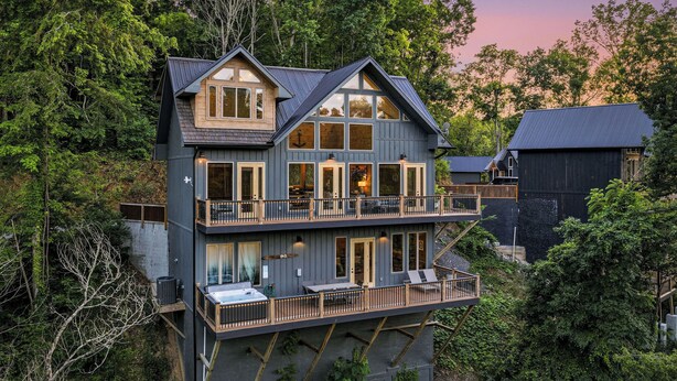 Ein mehrgeschossiges Haus mit Balkon, großen Fenstern und Blick auf den umliegenden Wald.