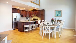 A spacious kitchen with dark wooden cabinets, a stainless steel refrigerator, and a central island with stools.