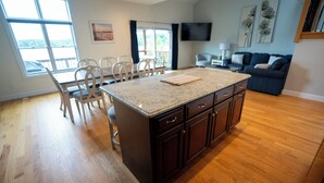 A spacious kitchen with a large island, wooden flooring, and a dining area with chairs.