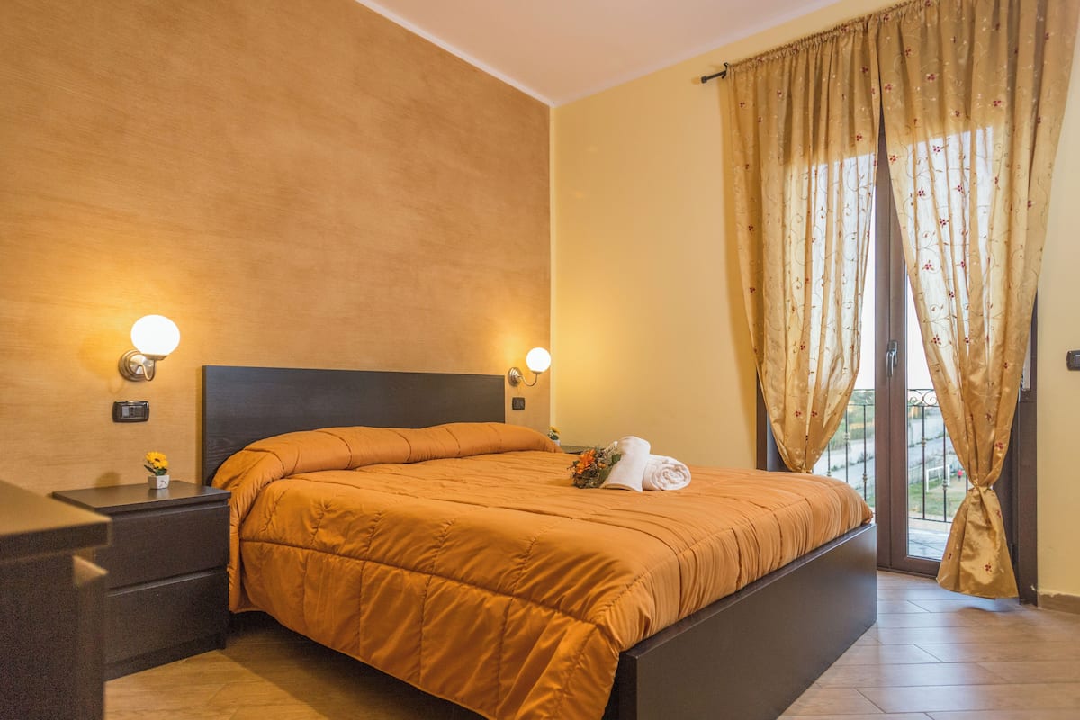 A bedroom with a large bed, two bedside tables, and a window with curtains.