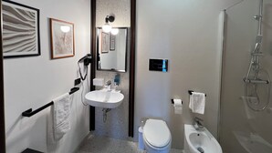 A modern bathroom with a sink, toilet, and shower. There are framed pictures on the wall and a towel rack. - B&B Monte (Giardina Gallotti)