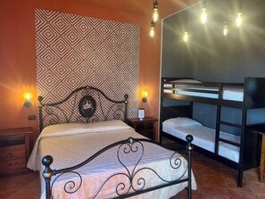 A bedroom with a patterned wallpaper, a bed with a decorative headboard, a nightstand, and a bunk bed.