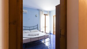 Ein Schlafzimmer mit Bett, einem Fenster mit Vorhängen und einer Tür.
