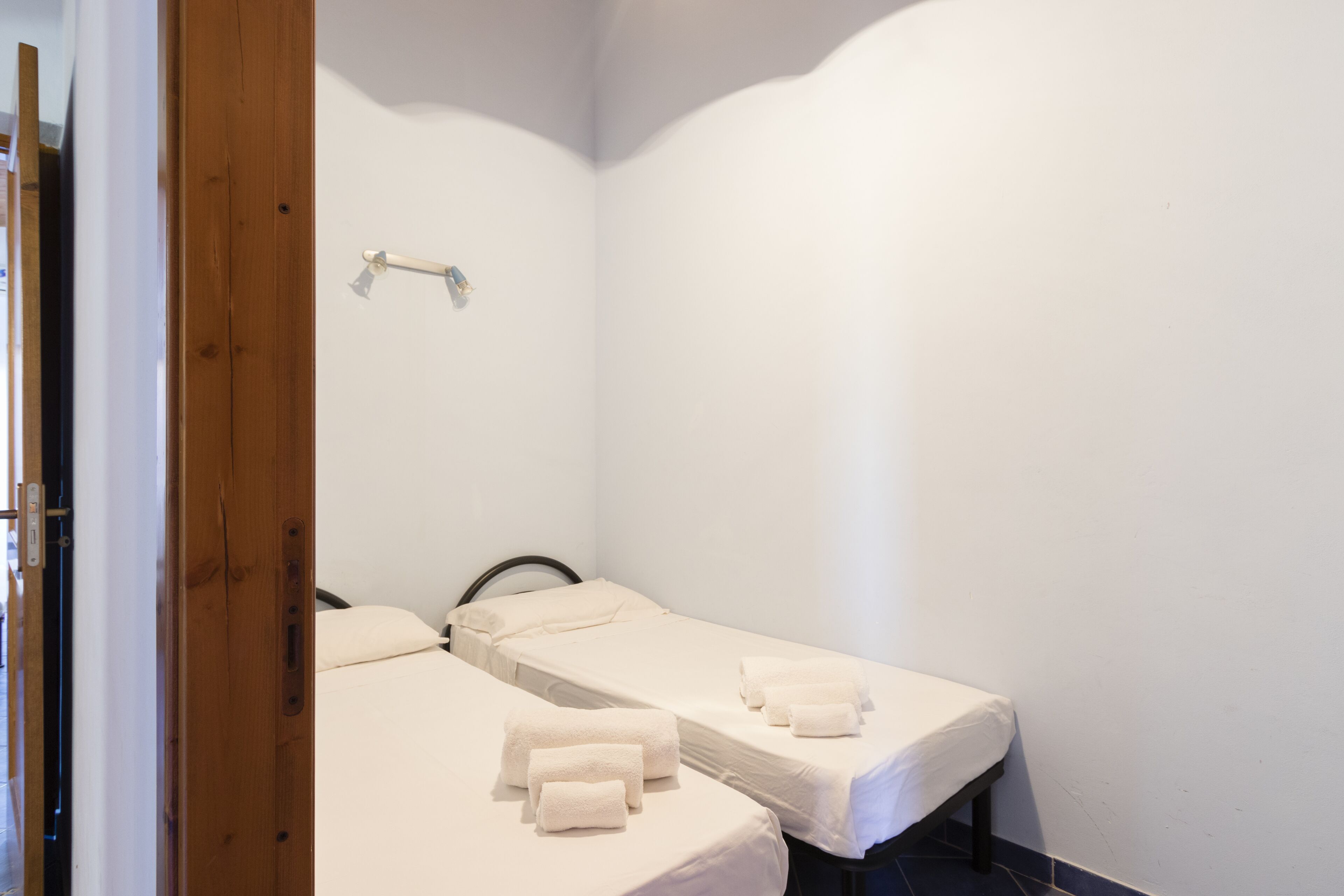 Une petite chambre propre, avec deux lits simples, chacun agrémenté d’une serviette blanche soigneusement pliée.